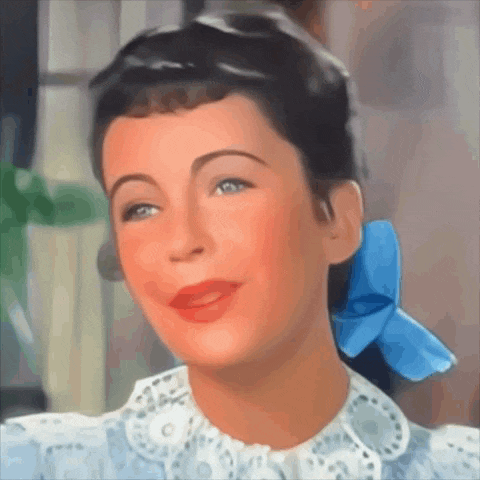 a woman with a blue bow in her hair smiles