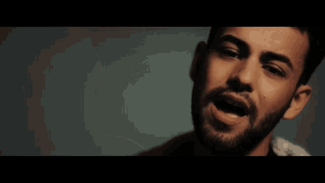 a man with a beard is looking at the camera with his mouth open