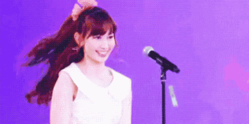 a woman is singing into a microphone on a stage .