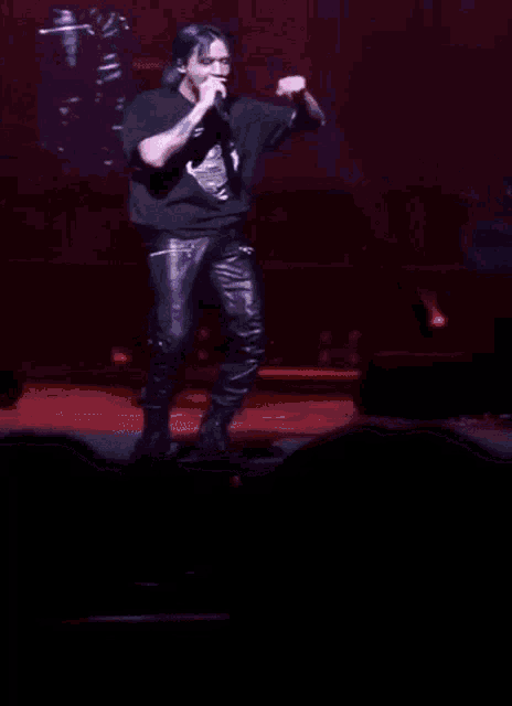 a man singing into a microphone on a stage in front of a large screen
