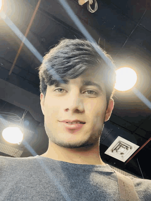 a young man taking a selfie in front of a ceiling light