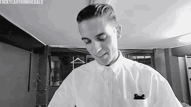a man in a white shirt is standing in a room with clothes hanging on the wall .