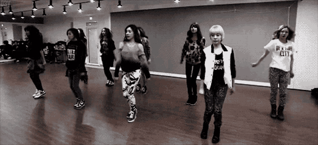 a group of young women are dancing in a dance studio and one of them is wearing a shirt that says detroit city
