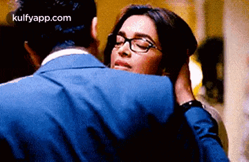 a man and a woman are hugging each other . the woman is wearing glasses .