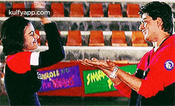 a man and a woman are clapping hands in front of a sign that says ' shark ' on it .