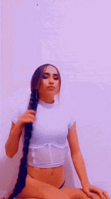 a woman with very long hair is wearing a white crop top