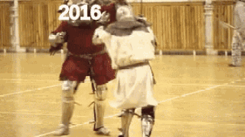two knights are fighting on a basketball court with the year 2016 on the bottom .