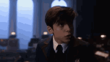 a young man in a suit and tie looks at the camera