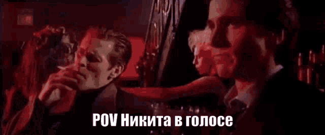 a man in a suit and tie is talking to another man in a dark room in russian .
