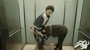 two men are standing next to each other in an elevator tied up with ropes .
