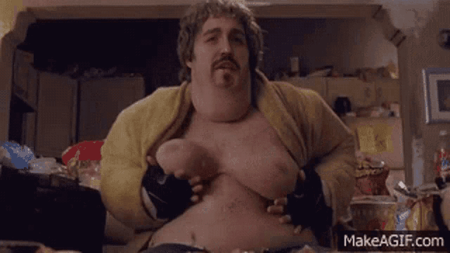 a fat man with a beard is sitting at a table with his shirt off