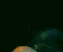 a man without a shirt is singing into a microphone while holding a blue object
