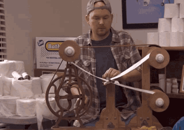 a man is working on a machine with a box of bath paper in the background