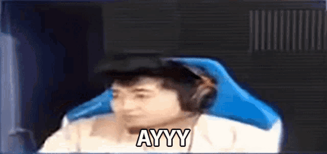 a man wearing headphones is sitting in a chair with the word ayyy written on his face .