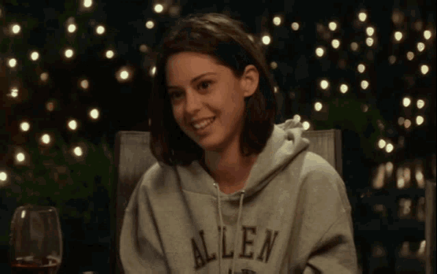 a woman wearing a allen sweatshirt is smiling while sitting in a chair .