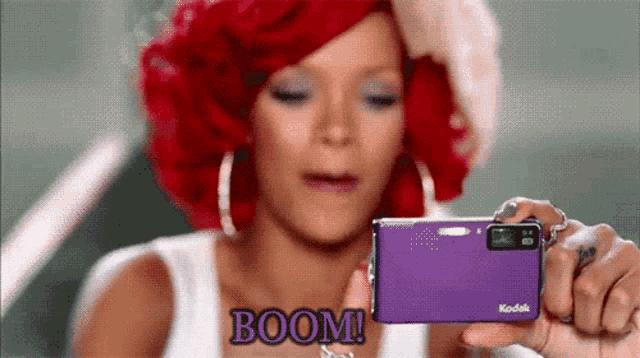 a woman is taking a picture with a purple kodak camera