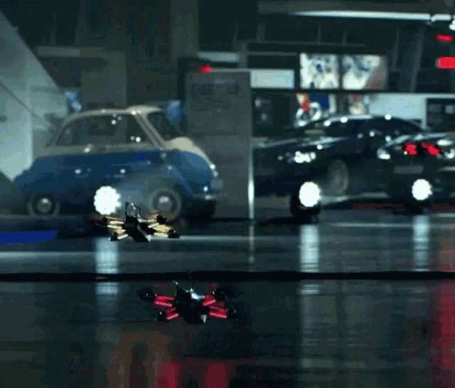 a blue car is parked next to a black car in a dark garage