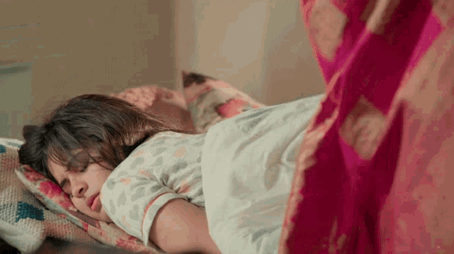 a woman is sleeping on a bed with a pink curtain