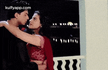 a man and a woman are hugging each other on a balcony .