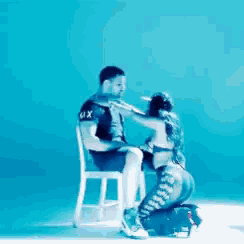 a man is sitting in a chair and a woman is kneeling down and touching him