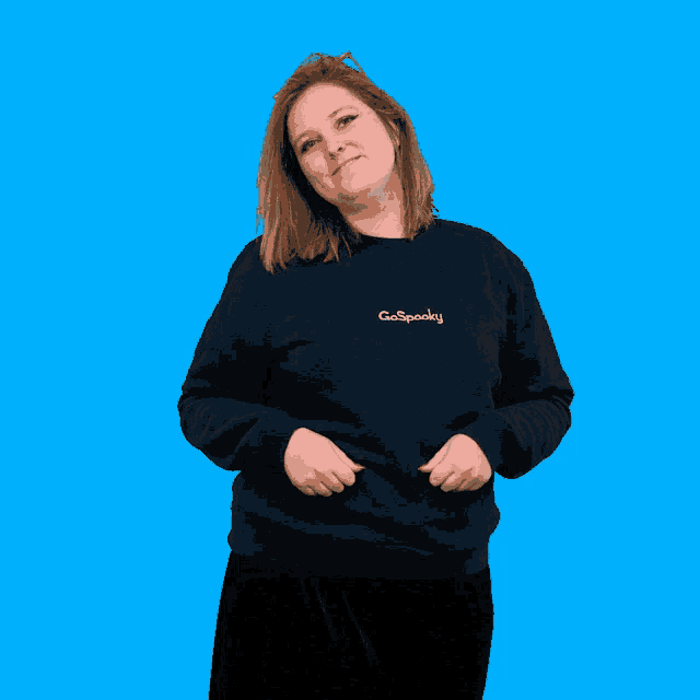 a woman wearing a sweatshirt that says go spooky gives two thumbs up