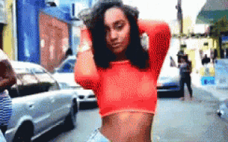 a woman in a red crop top is standing on a city street
