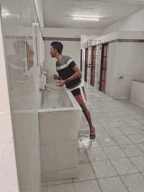 a man washing his hands in a bathroom with a shirt that says calvin klein on it