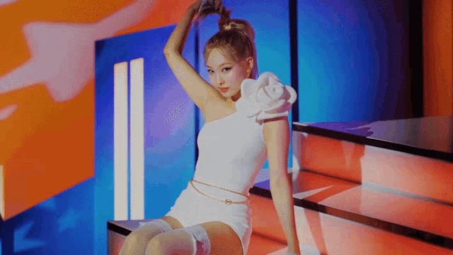 a woman in a white dress is sitting on a staircase holding her hair in a ponytail