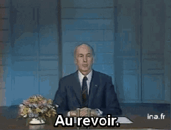 a man in a suit and tie is sitting at a desk with the words au revoir written on it