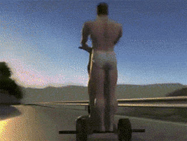 a man in underwear is riding a scooter on a road