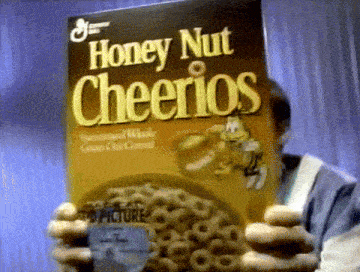 a man holds a box of honey nut cheerios