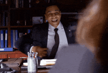 a man in a suit and tie is sitting at a desk with a pen holder