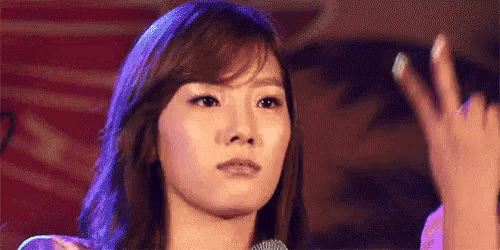 a woman is waving her hand in front of a microphone and making a face .