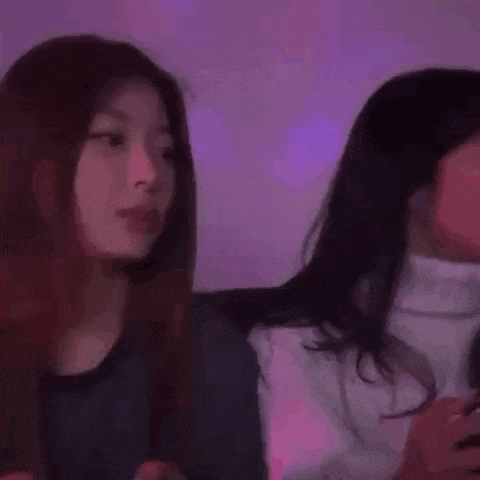 two women are sitting next to each other in a dark room .