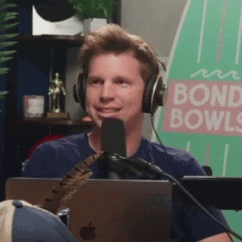 a man wearing headphones sits in front of a microphone in front of a sign for bond bowls