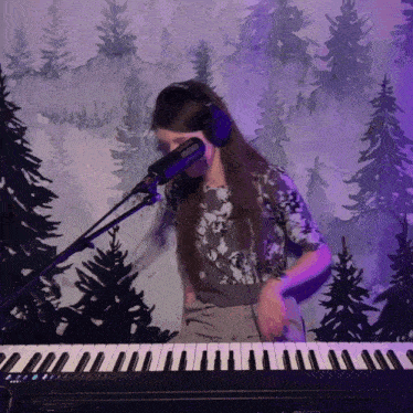a woman singing into a microphone while playing a piano