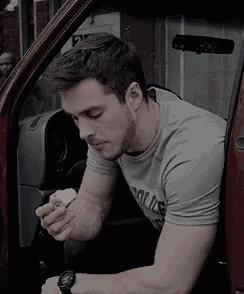 a man is sitting in the driver 's seat of a red truck eating a banana .