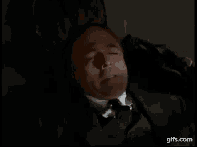 a man in a suit and tie is laying down in a chair with his eyes closed .