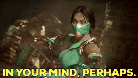 a woman in a green costume with a mask on her face is standing in a dark room .