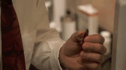 a man in a white shirt and red tie is holding a piece of food in his hand .