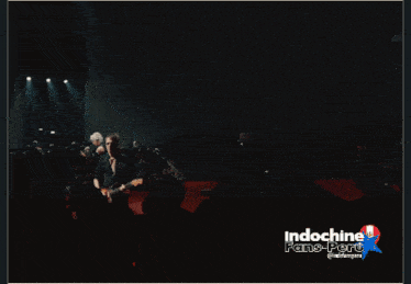 a man playing drums in front of a crowd with the words indochine fans-port on the bottom right