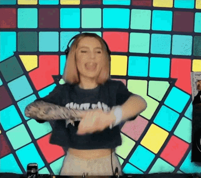 a woman wearing headphones is dancing in front of a colorful wall
