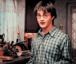 a young man wearing glasses and a plaid shirt is standing in front of a kitchen counter .