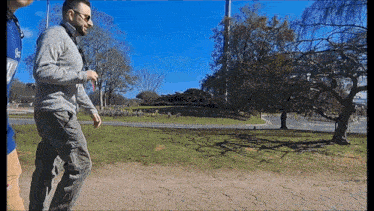 a man in a grey sweater is walking down a sidewalk