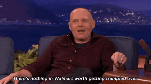 a man sitting on a couch laughing and saying there 's nothing in walmart worth getting trampled