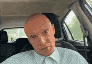 a man with a bald head is sitting in a car