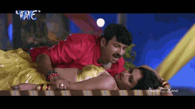 a man in a red shirt is laying on a woman 's stomach in a video that says navel zone