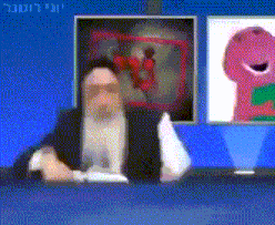 a man with a beard is sitting at a desk in front of a screen with a picture of barney on it