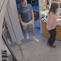 a man wearing a blue shirt that says ' brooklyn ' is standing next to a woman in a pink sweater