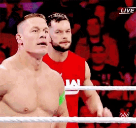 two men are standing in a wrestling ring and one of them is wearing a red shirt that says i am .